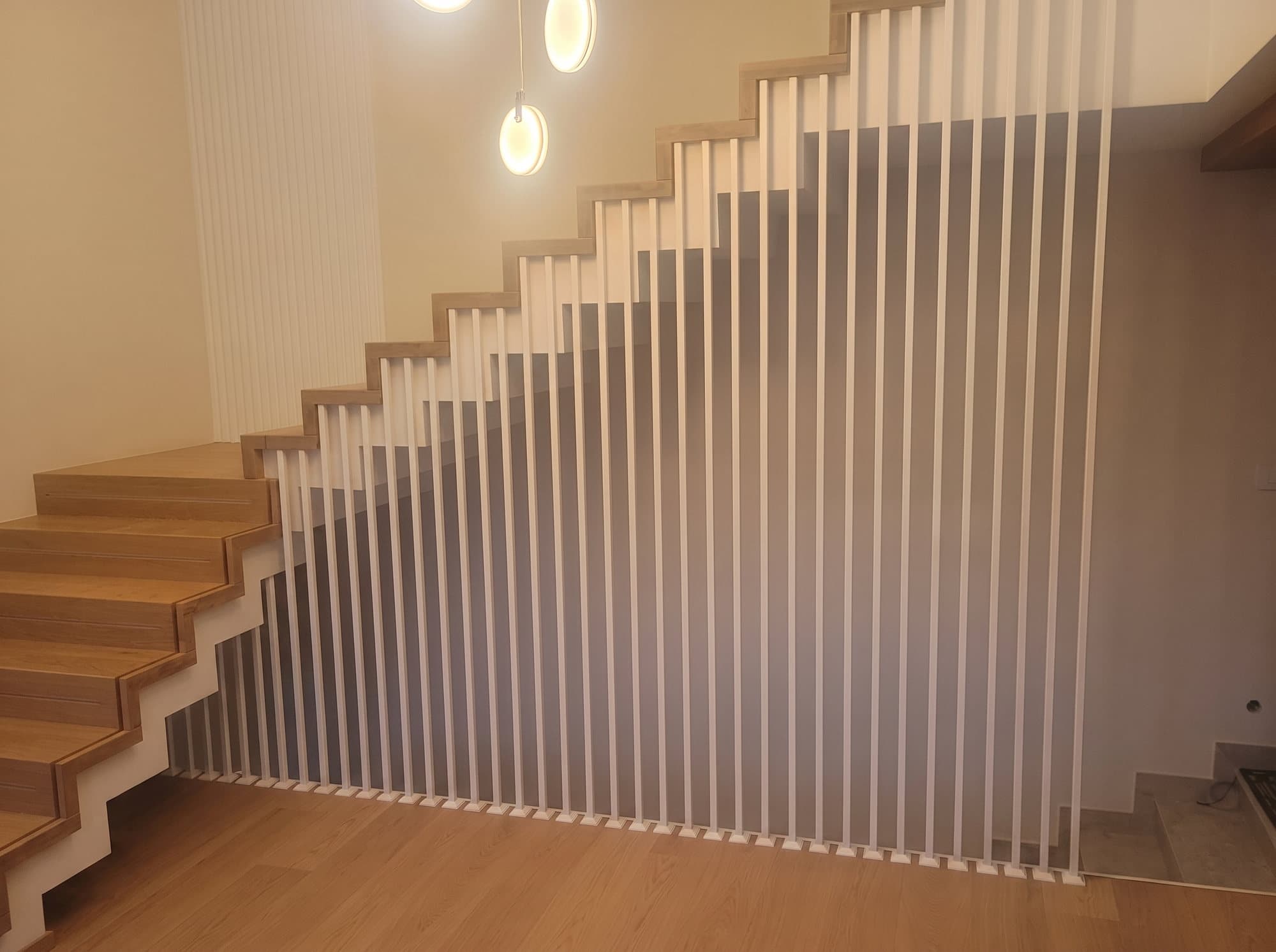 Balustrada z gęstych pionowych prętów wzdłuż schodów w jasnym wnętrzu